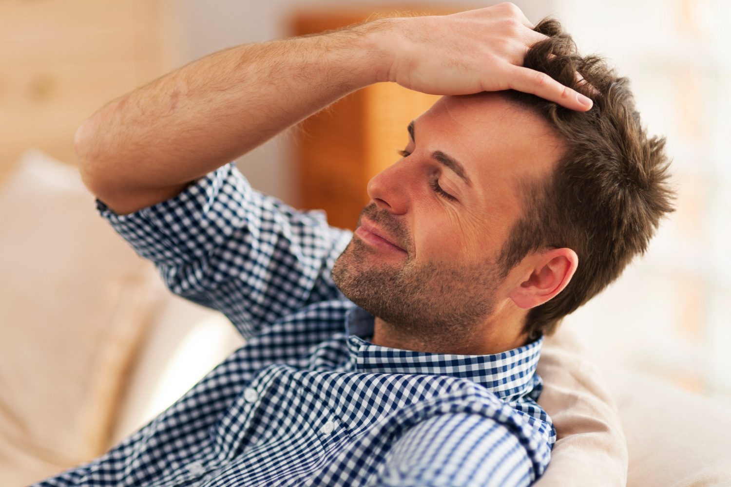 Man relaxing with his eyes closed, hand resting on his full head of hair