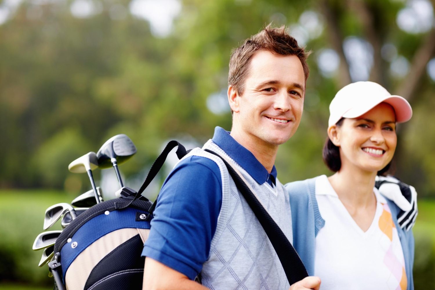Smiling couple carrying golf clubs together on a golf course
