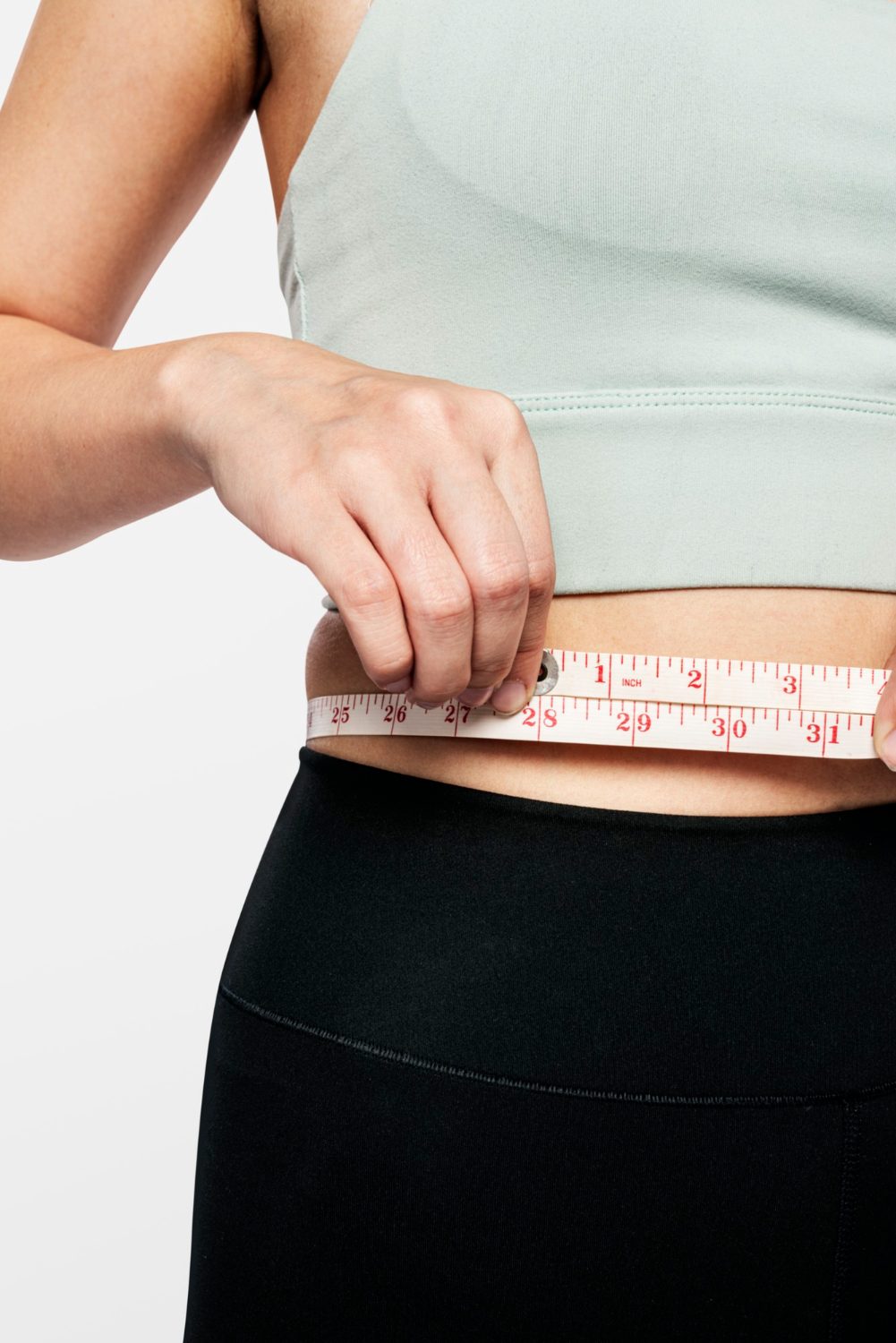 Woman in activewear checking her waistline, focused on her health goals